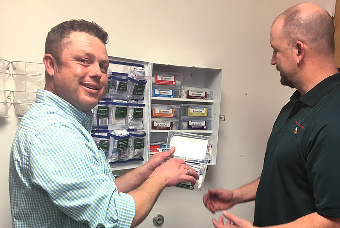 Two sales people looking at first aid station