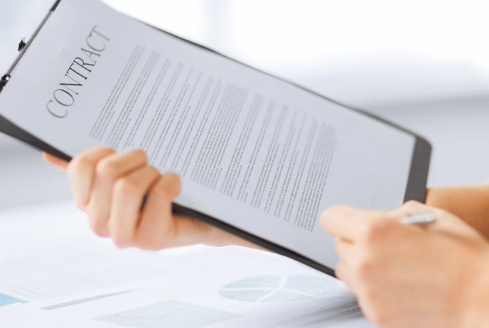 Image of person signing a contract on clipboard